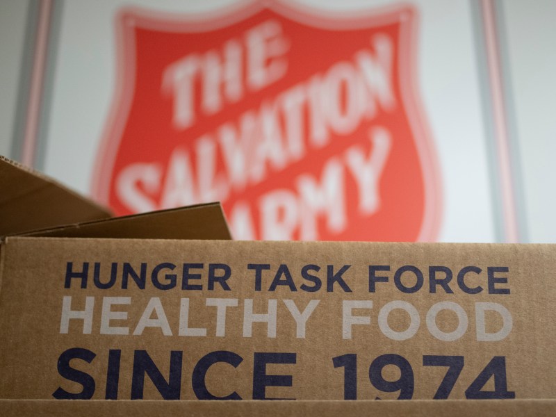 A box says "HUNGER TASK FORCE. HEALTHY FOOD SINCE 1974." The Salvation Army sign is out of focus in the background.
