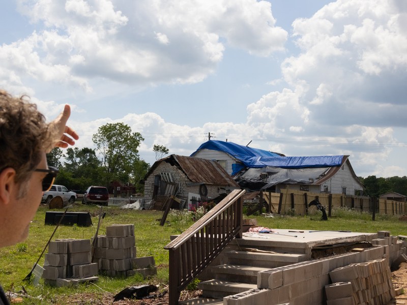 Person points toward damaged buildings.
