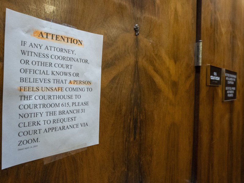 A printed notice taped to a wooden courtroom door informs attorneys, witness coordinators, and court officials that if anyone feels unsafe attending court in person, they may request a Zoom appearance by notifying the Branch 31 clerk. Key words like “ATTENTION” and “A PERSON” are highlighted in orange. The notice is dated April 14, 2025, and the door has signage identifying it as Courtroom 615.