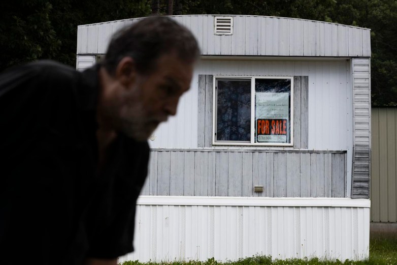 Person's silhouette against a home with a for sale sign in window