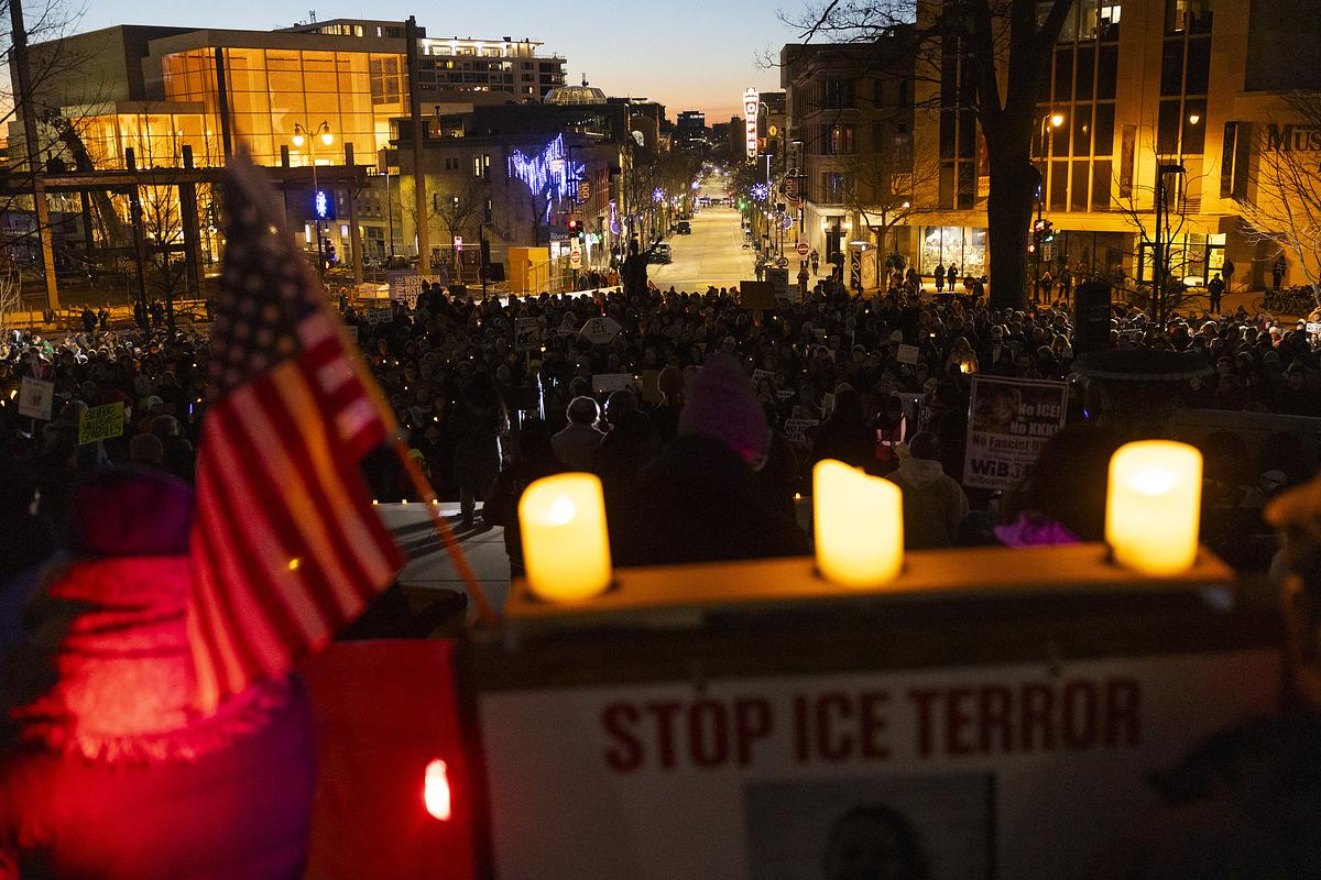 Candles and an American flag are foreground a scene of Madison cityscape at twilight.