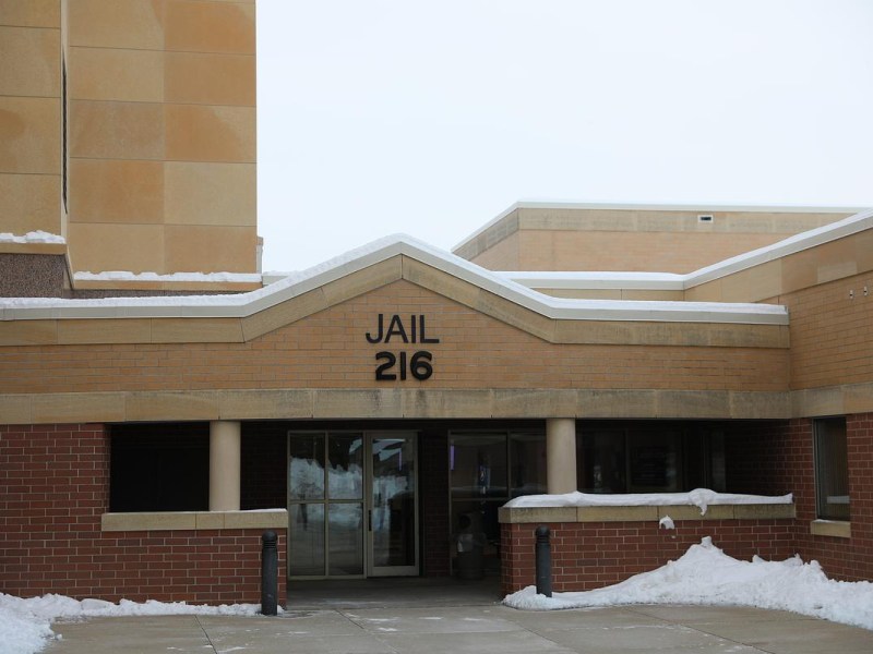 Snow-covered brick and tan building with the text "JAIL 216" above a glass door