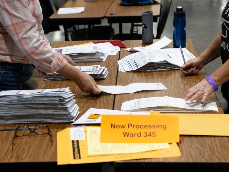Arms of two people handling ballots on a table