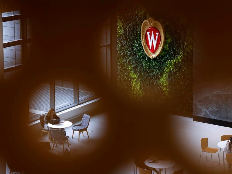 W sign on a wall of greenery and people sitting at tables