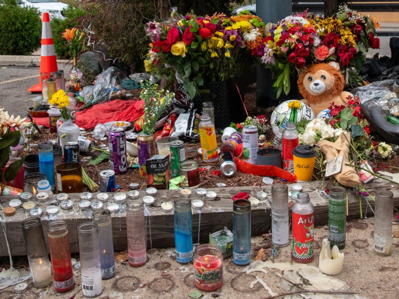 Flowers, candles and other mementos next to a parking lot