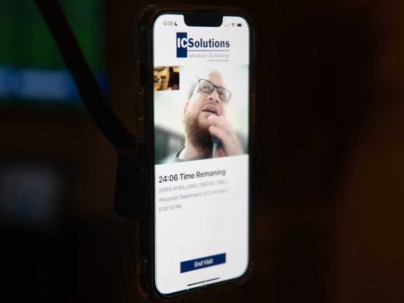 A smartphone screen displays a video call on the ICSolutions app showing a person with glasses and a beard, with text reading "24:06 Time Remaining" and an "End Visit" button at the bottom.