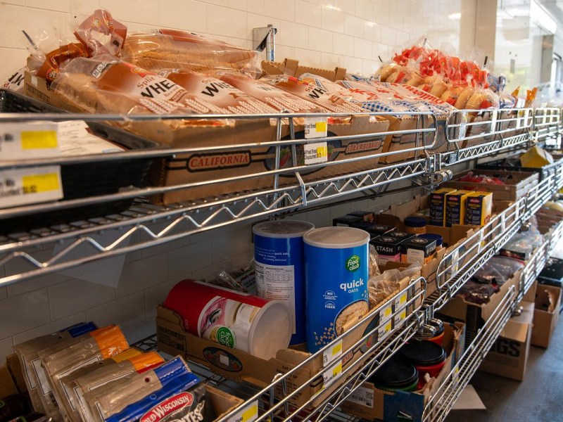 Metal shelves stocked with packaged bread, oats and other grocery items