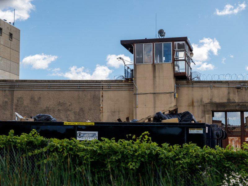 A concrete wall of a prison with a guard tower