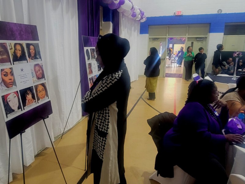 Woman looks at display of women's faces.