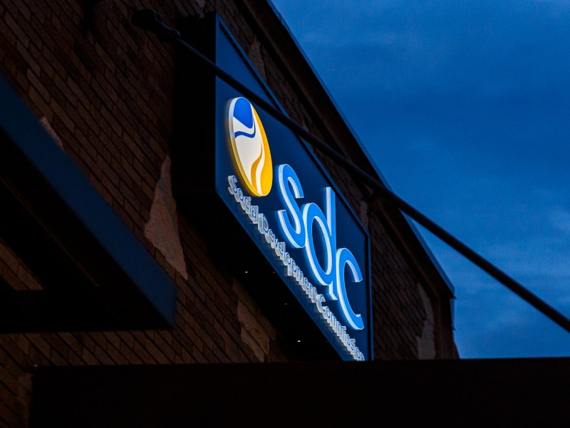 Blue and yellow SDC sign on dark building